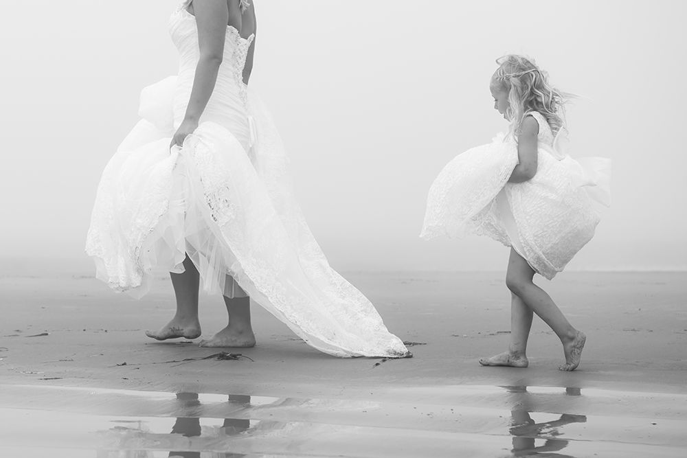 Wedding couple playfully running and splashing through ocean waves.