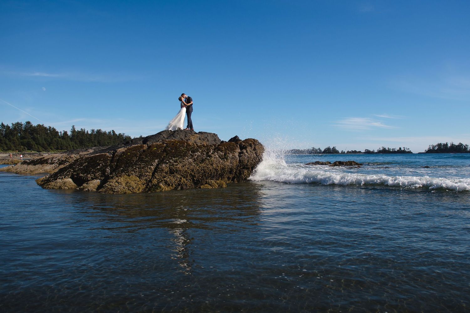 Panoramic coastal landscape with rocky outcrops and distant islands in blue ocean waters.