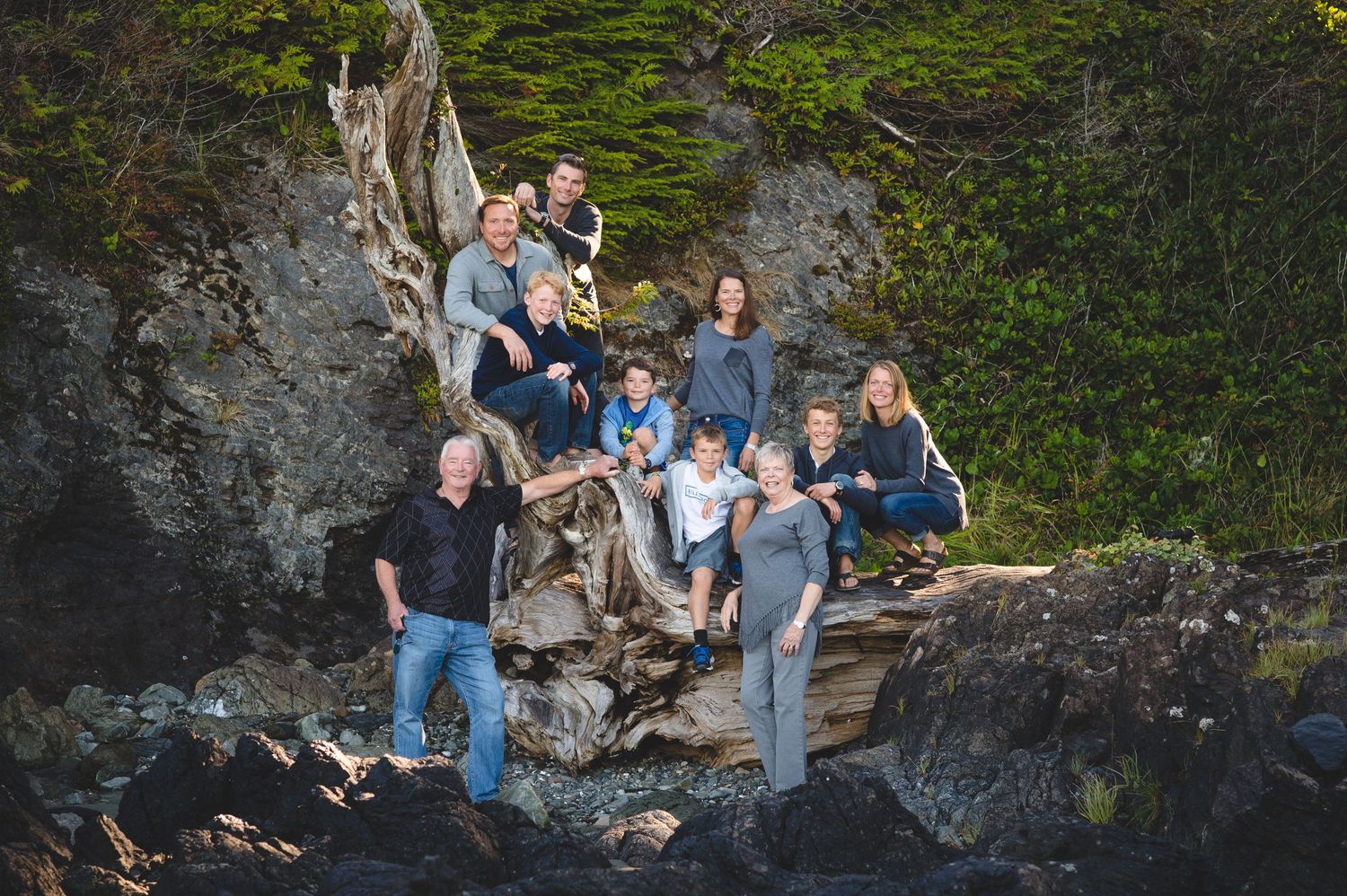 A group of people sitting together on rocky terrain surrounded by green foliage in a natural outdoor setting.