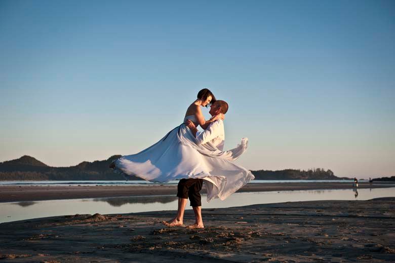 A romantic beach photoshoot at sunset with a flowing white dress catching the ocean breeze.