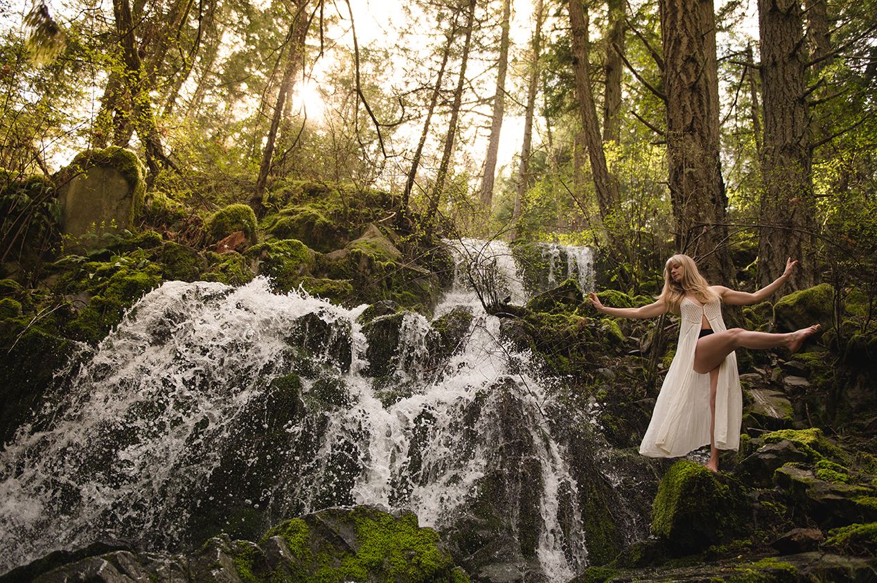 Splashing water droplets create ethereal patterns in a sunlit forest setting.