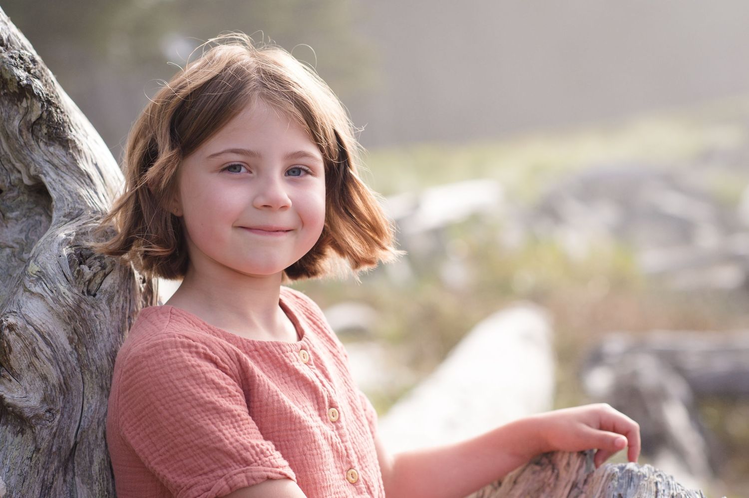 Natural light illuminates a beachside portrait against weathered driftwood.