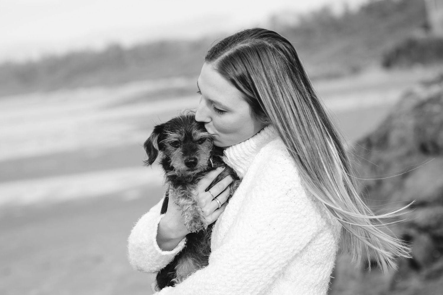 Black and white dog looking lovingly at its owner against light background.