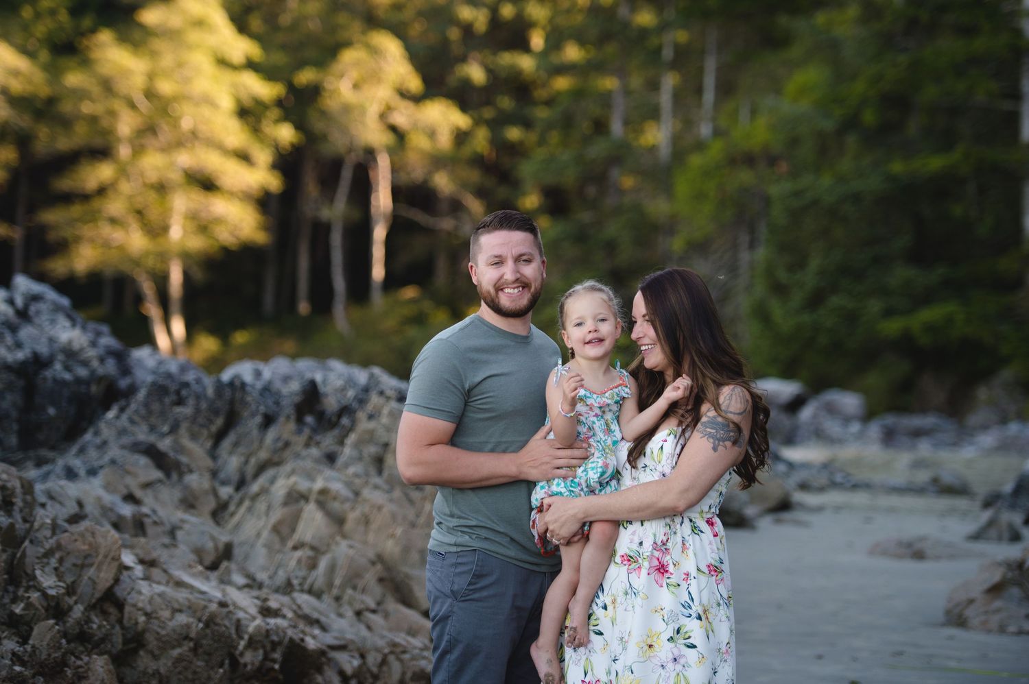 A joyful family enjoying time together on a rocky beach with forest backdrop.