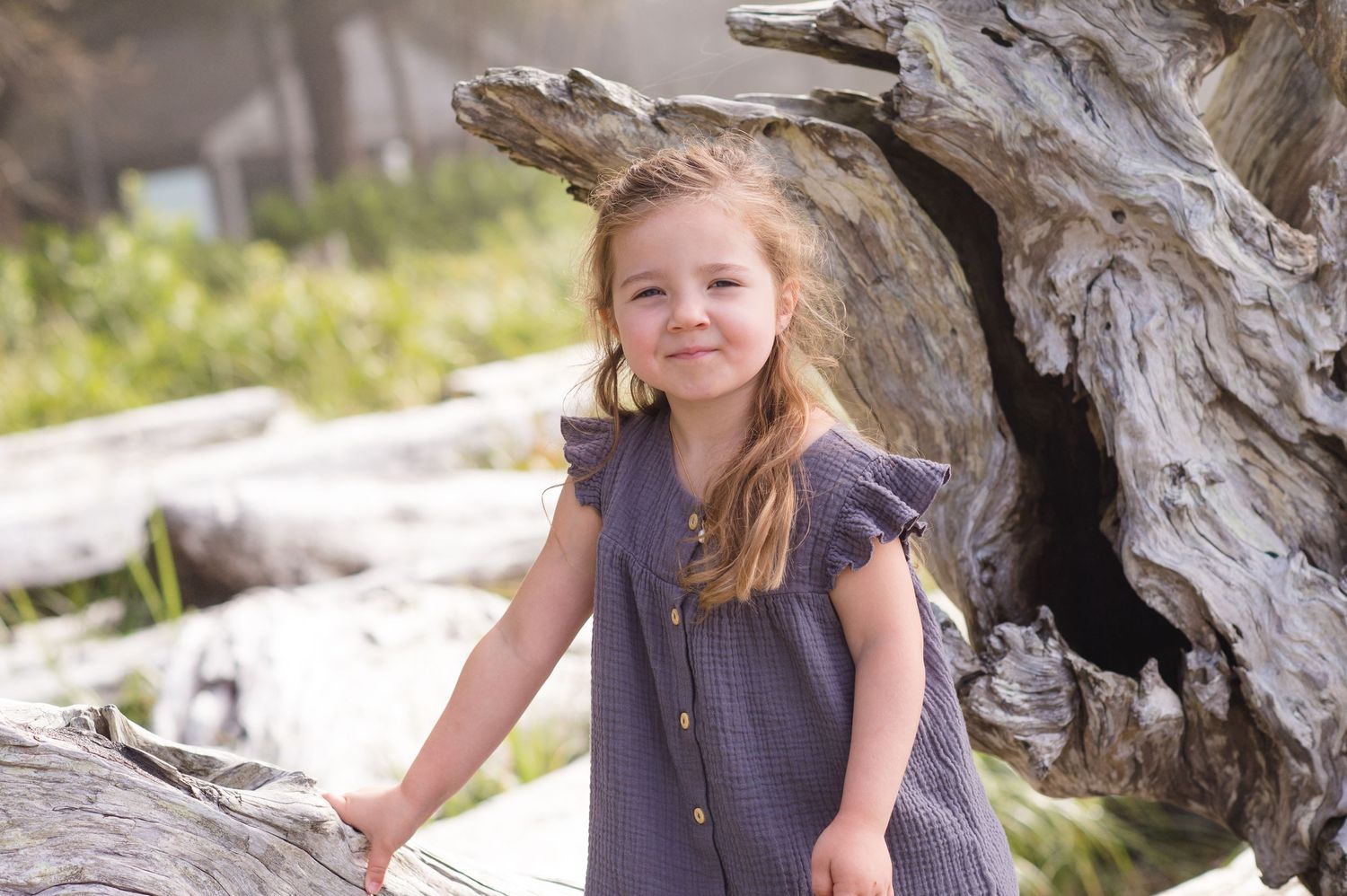 Casual outdoor portraits taken along a driftwood-strewn beach.