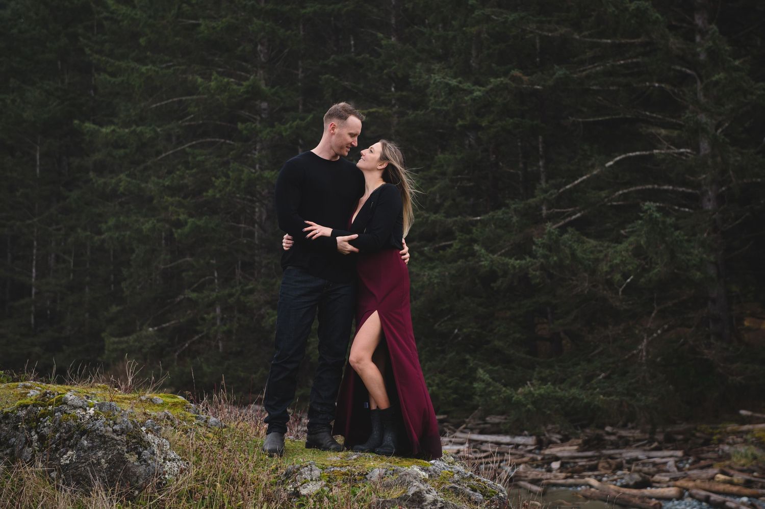 Couple exploring forest path surrounded by tall evergreen trees.