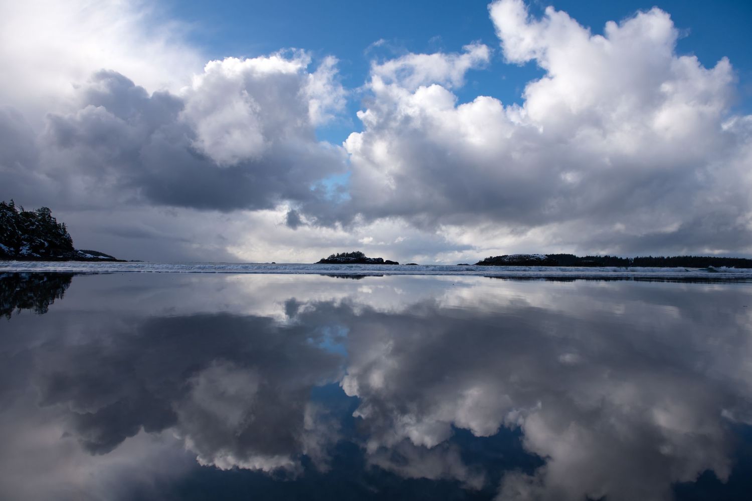 Dramatic cloudscape over ocean waters with dark storm clouds reflecting on the calm sea surface.