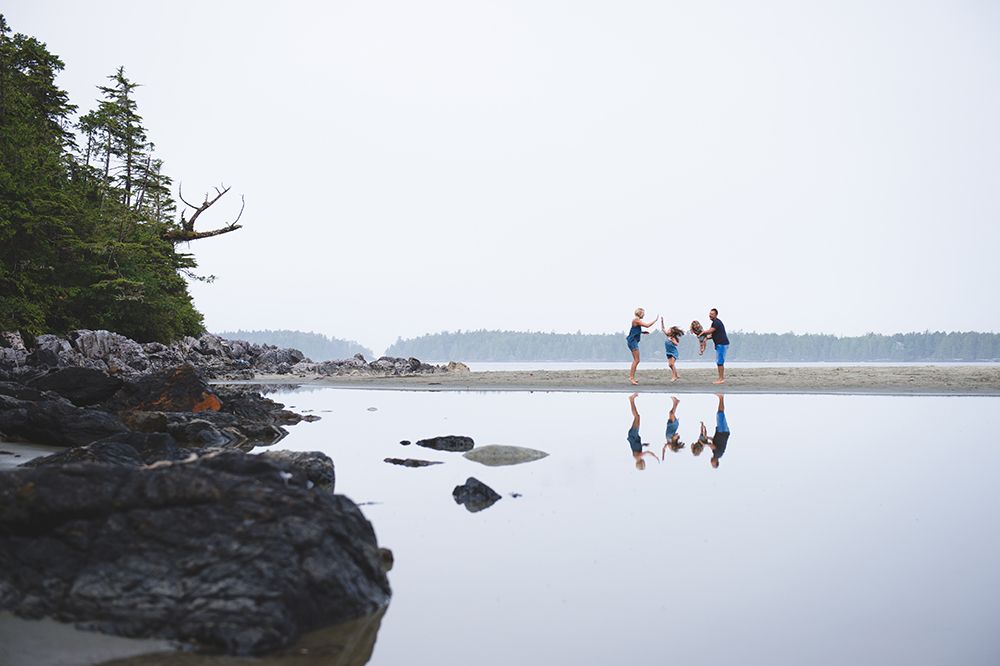 Distant figures walking along a rocky shoreline with calm water and islands in the background.
