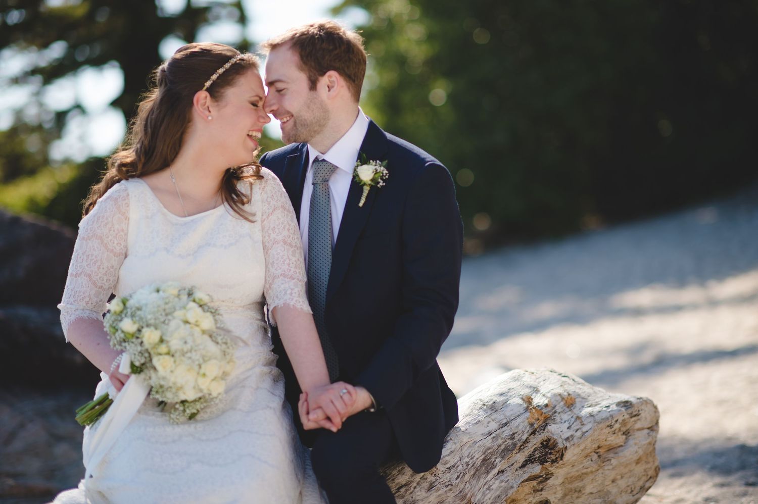 Romantic wedding couple portraits on sunny beach with natural coastal backdrop.