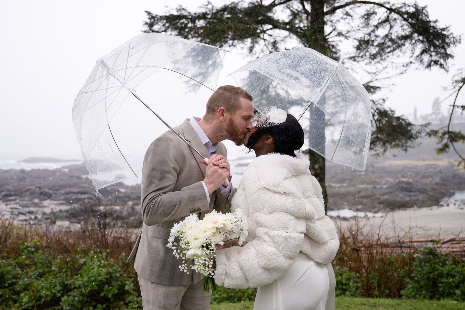 Wedding couple shares a romantic moment on a misty cliff overlooking the Pacific Ocean.