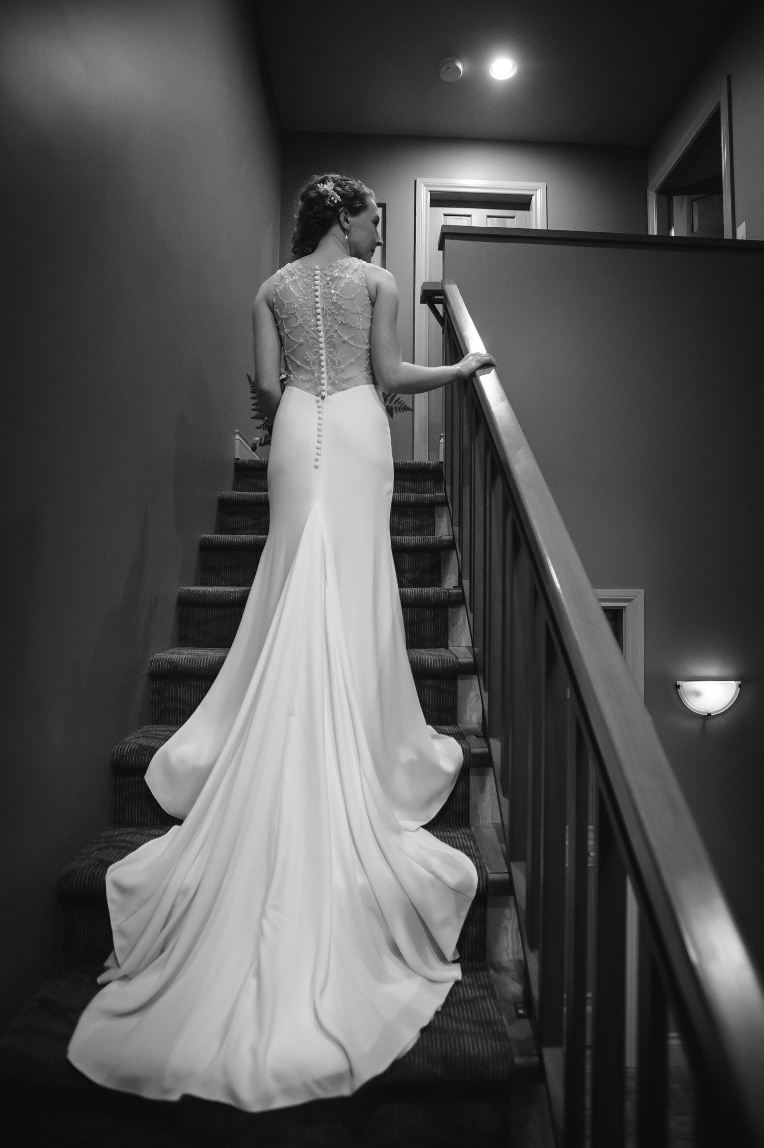 Black and white photograph showing the back of an elegant white wedding dress with flowing fabric and train.