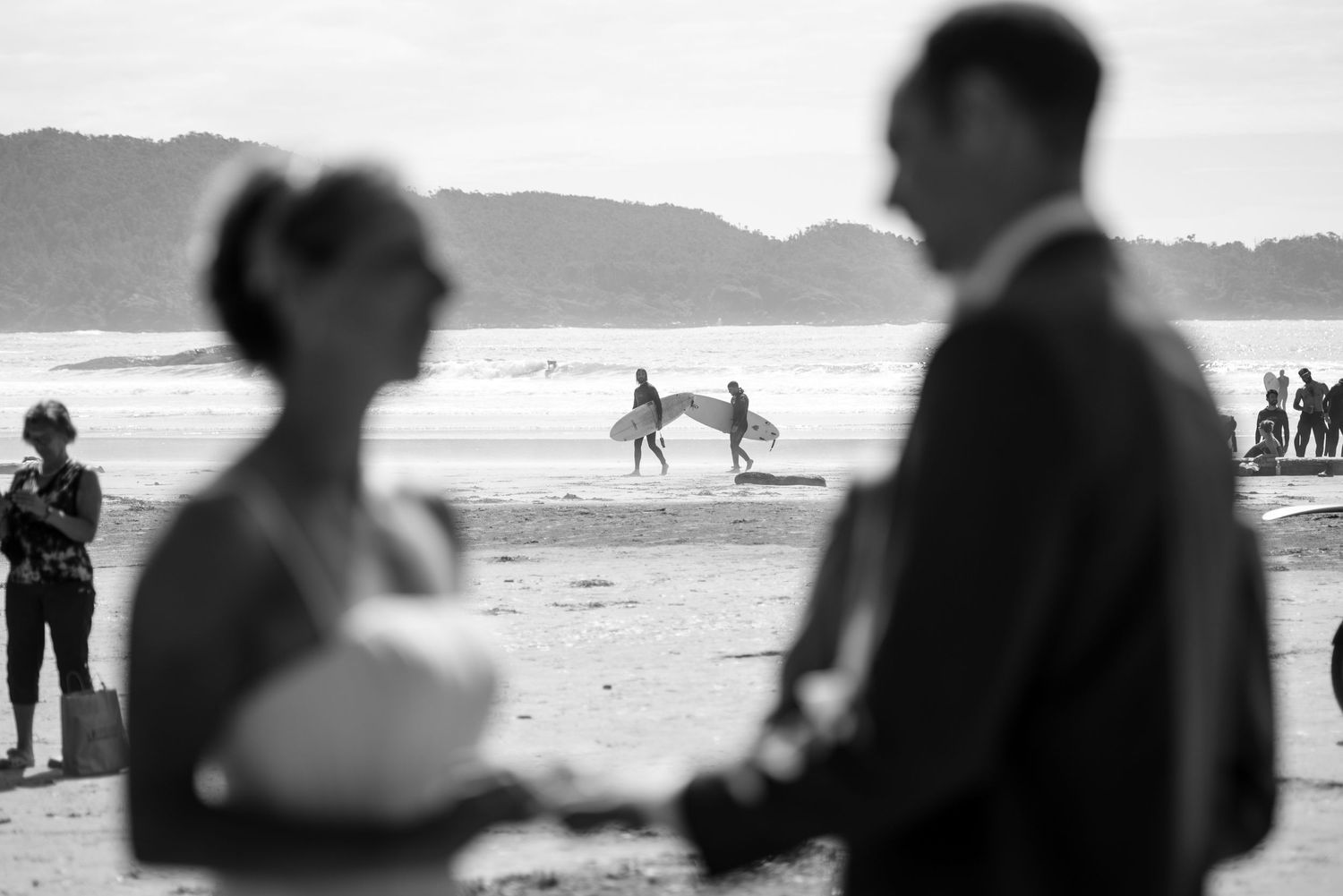 Couple walking along a misty beach shoreline at sunset.