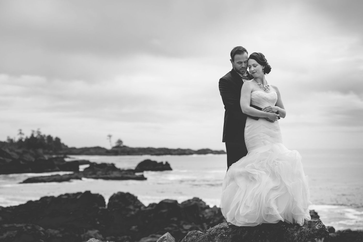 Dramatic black and white coastal wedding portraits with stormy skies.