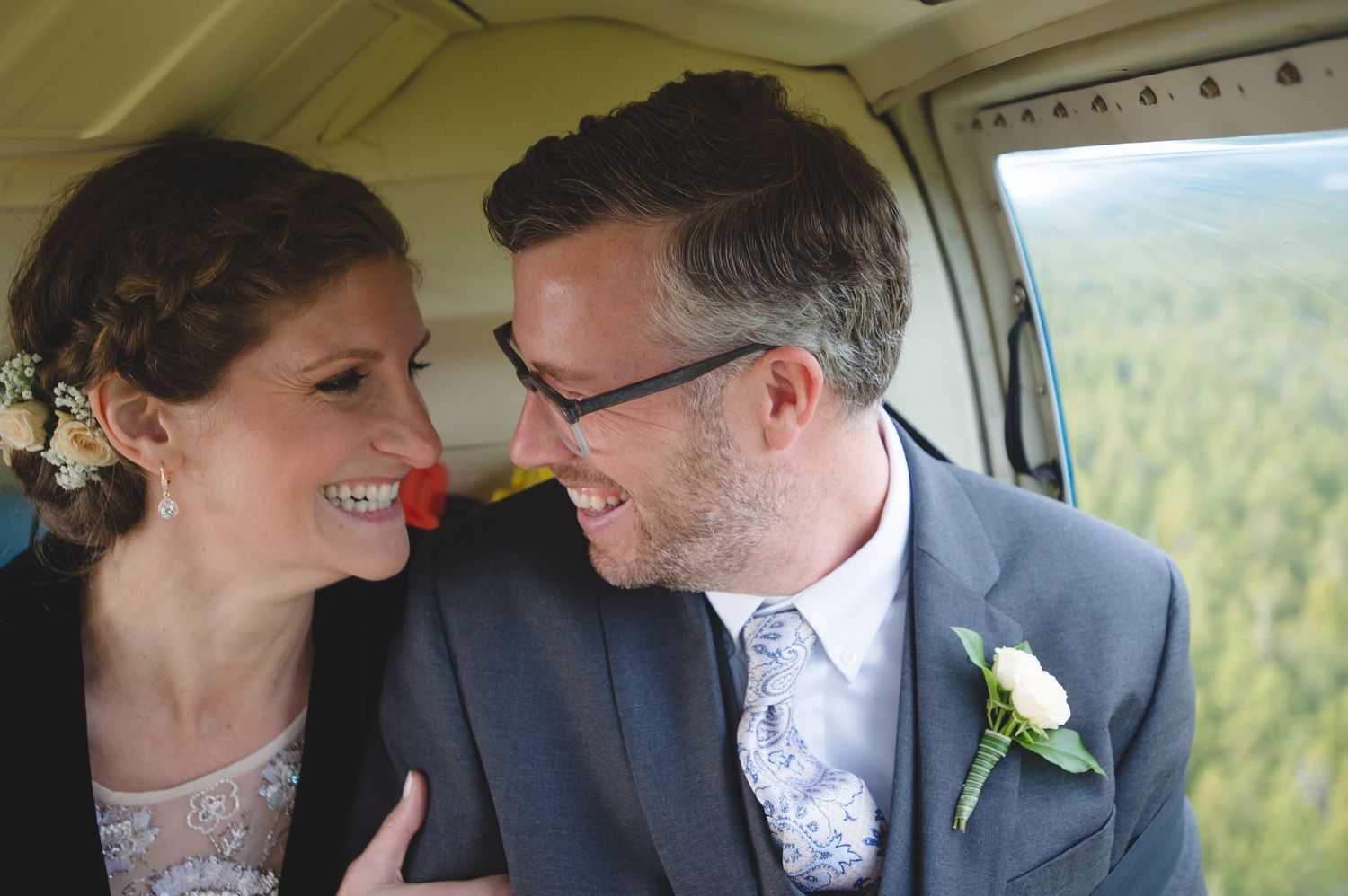 A couple shares intimate moments inside a helicopter while flying over mountain terrain.