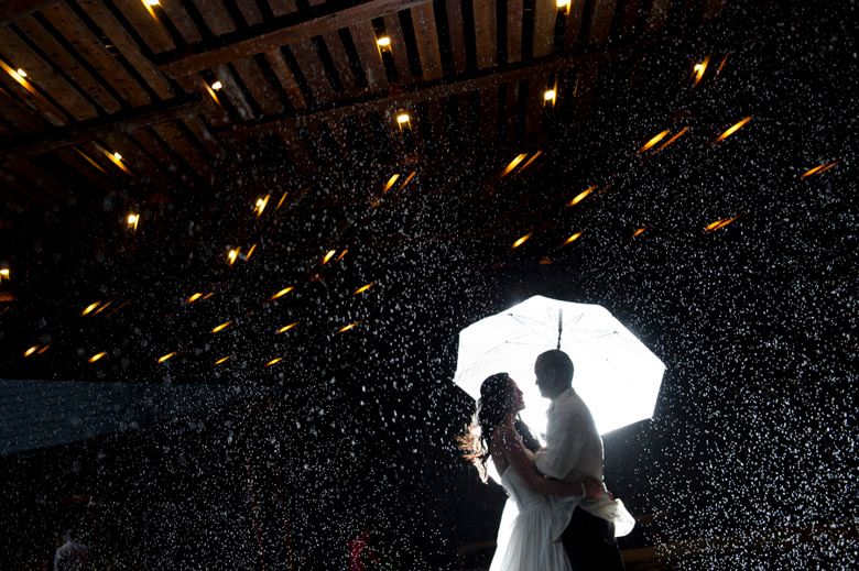Silhouettes against dark night sky with glowing sparklers creating light trails.