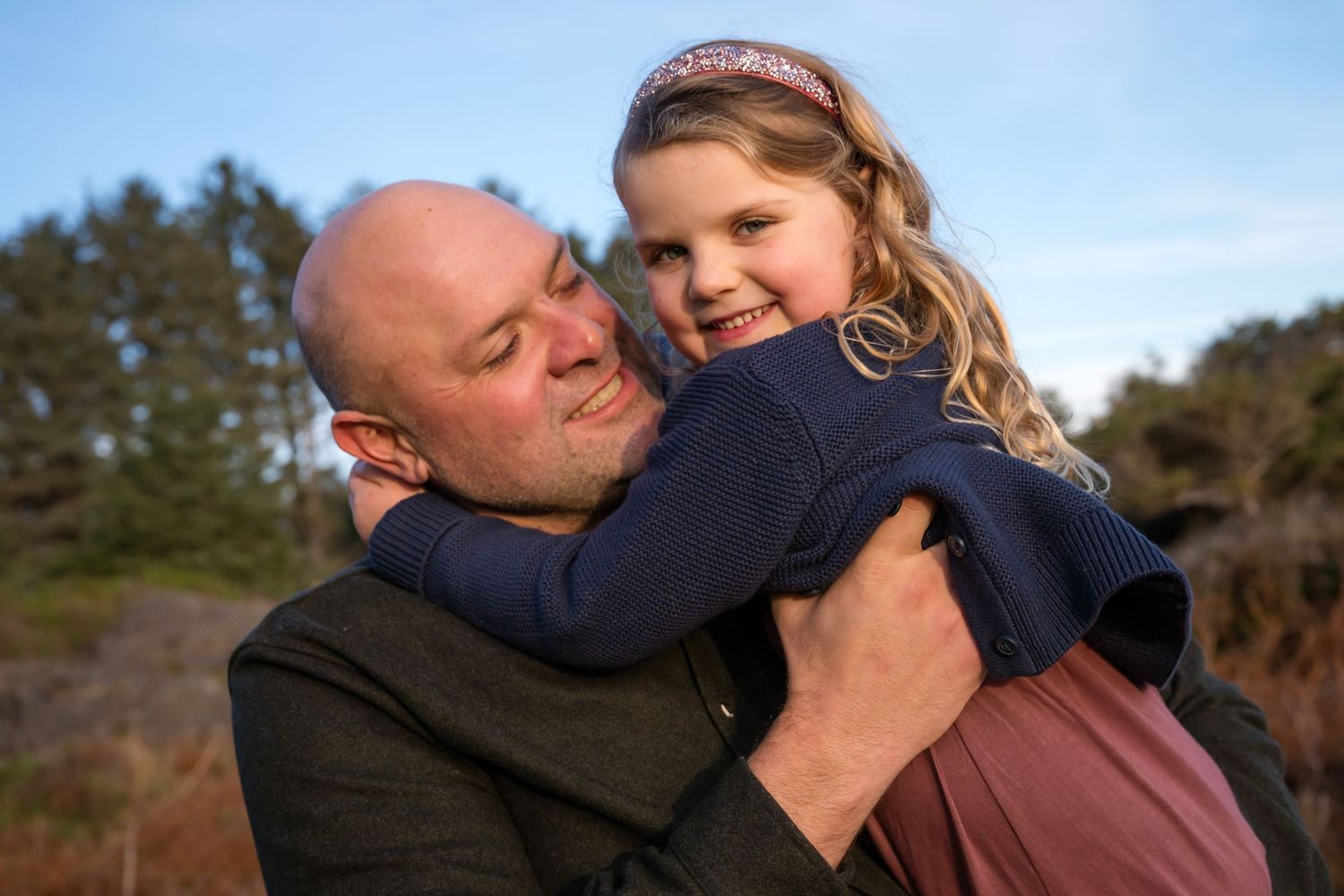 Two people share tender moment on coastal cliffs during outdoor photo session.