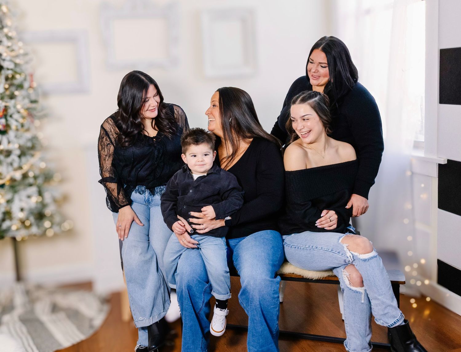 Family members in coordinated outfits sit together on a light colored floor.