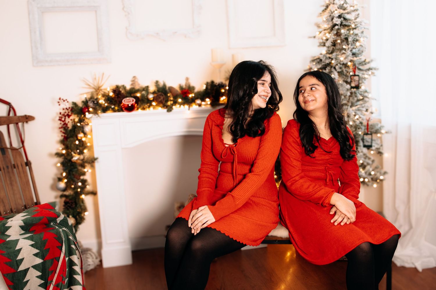 Family members in coordinated red and black outfits posing in front of Christmas tree and decorations.