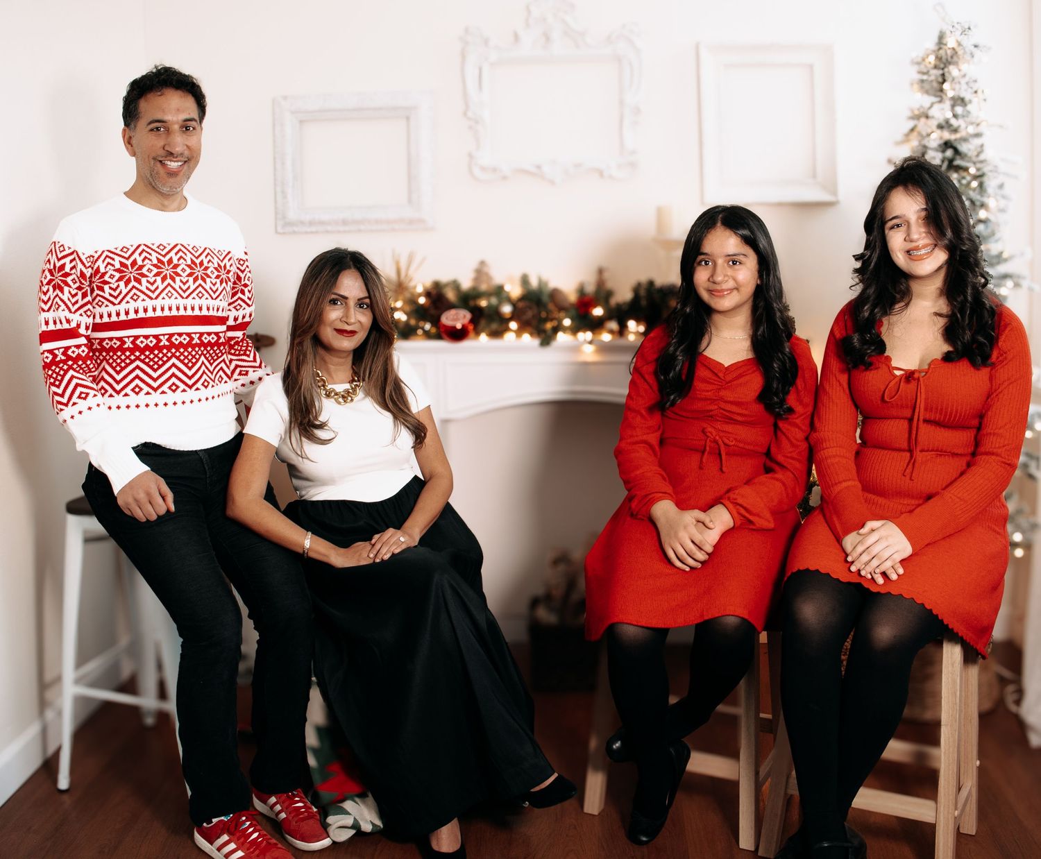 Family wearing red and black holiday outfits posing in front of Christmas decorations.