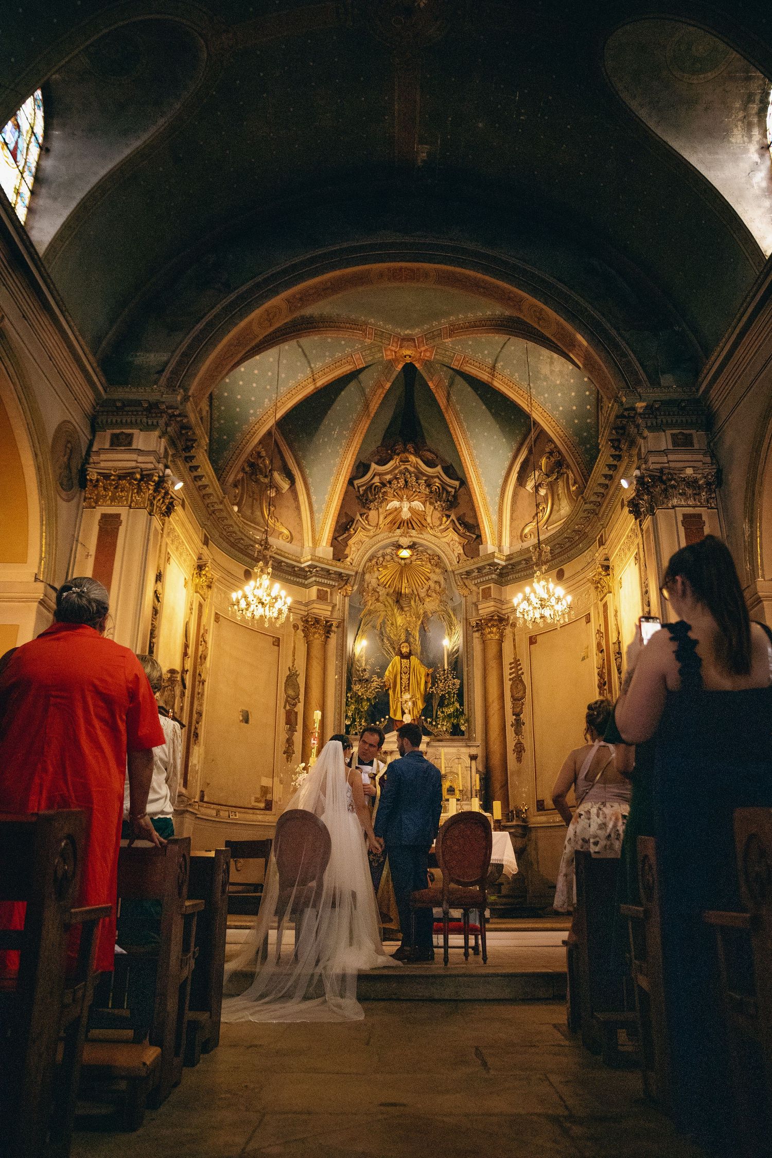 Ornate church interior with vaulted ceilings and golden decorations during a wedding ceremony.