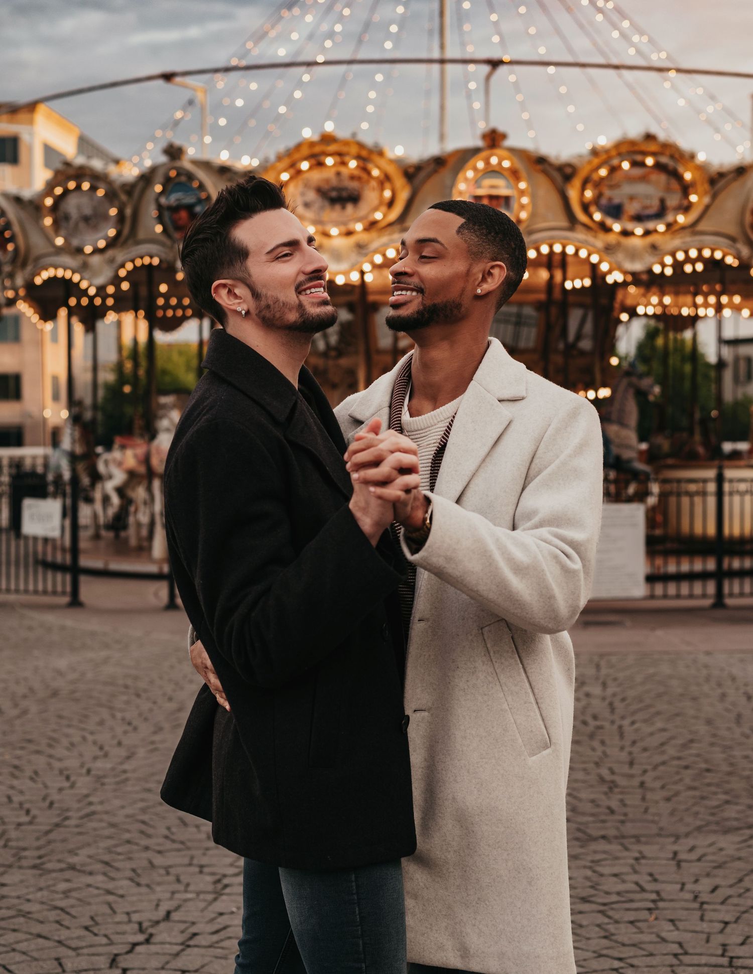 Two grooms embracing after proposal at Bridge Street Town Centre carousel