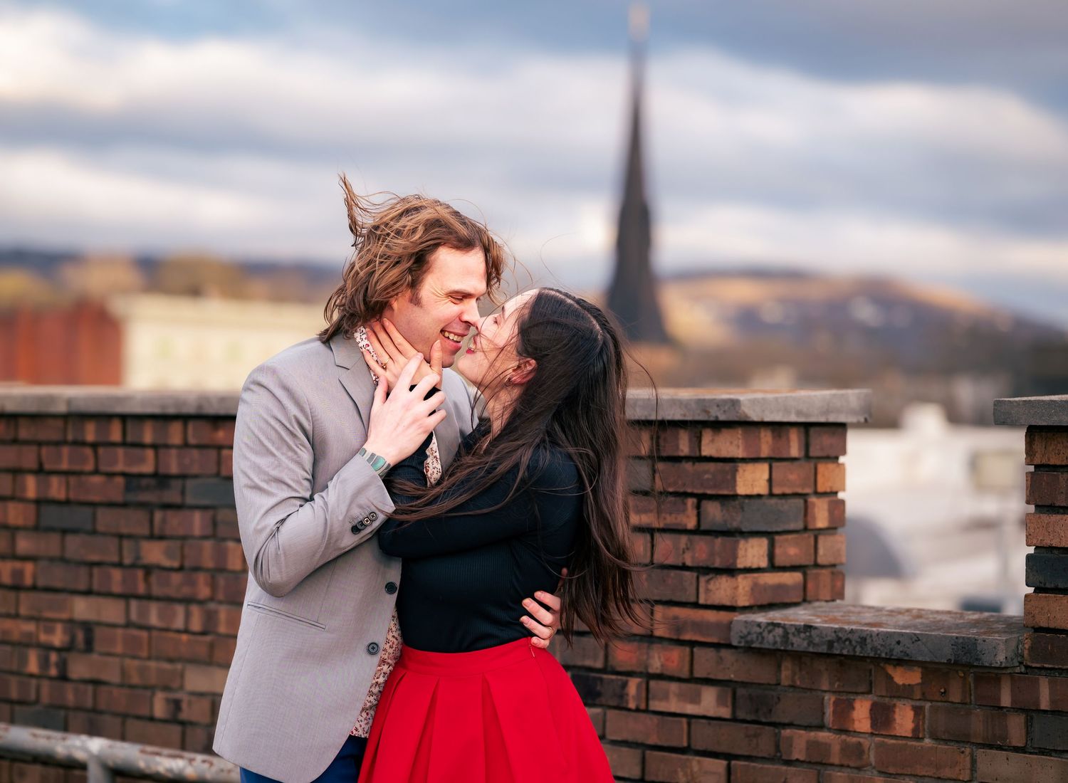 Moody, cinematic photo of couple embracing on rooftop, nose to nose, smiling and about to kiss in downtown Huntsville, Alabama.