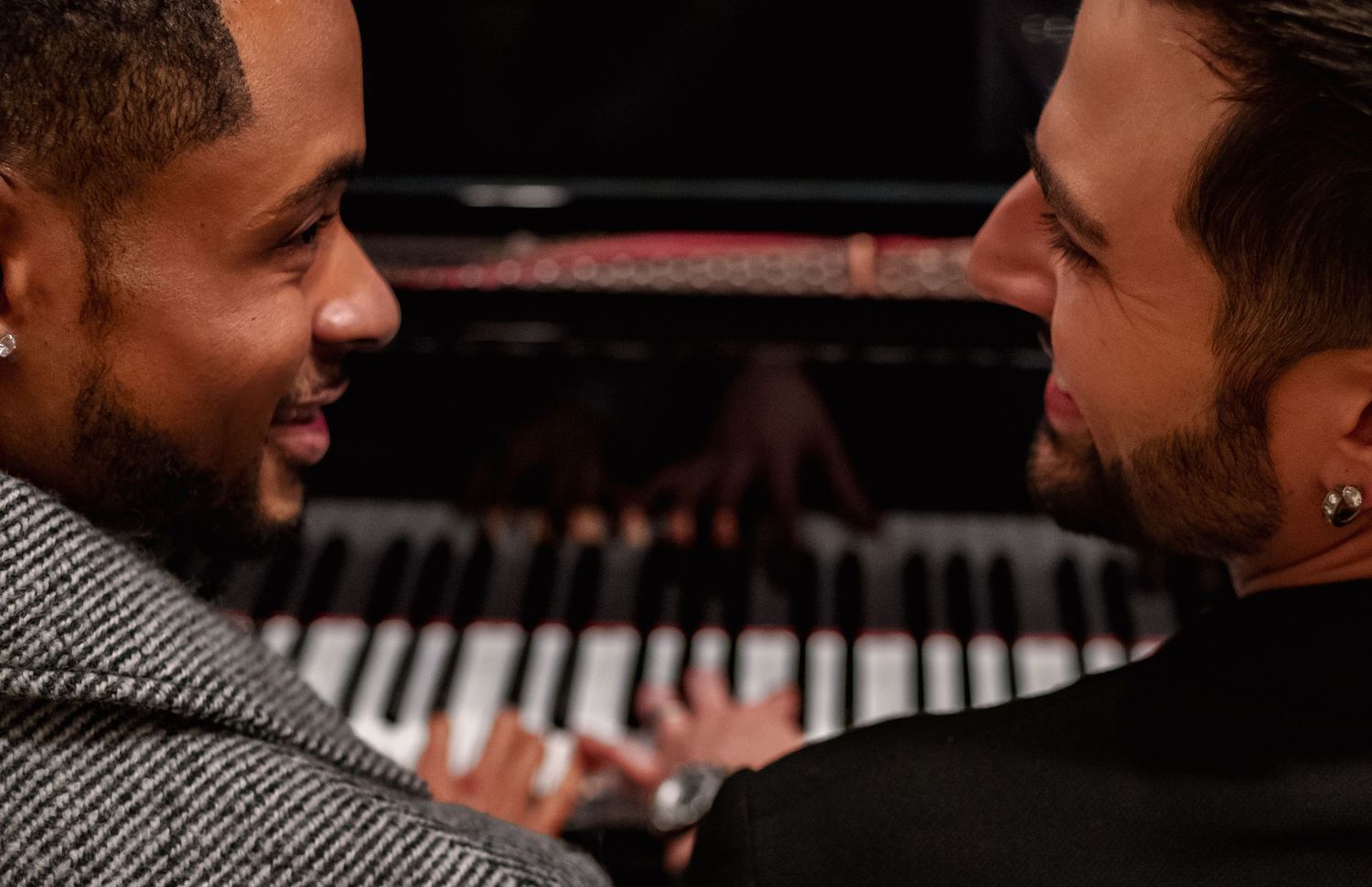 Two grooms sitting at baby grand piano inside The Westin Huntsville