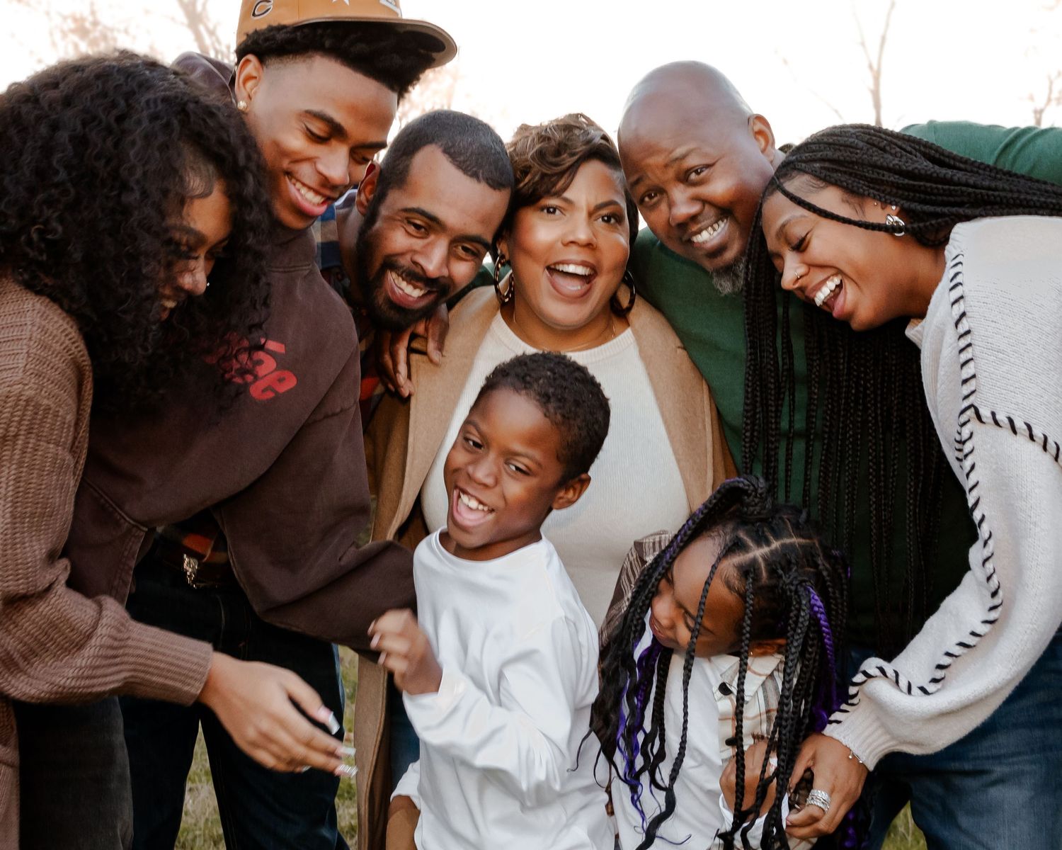 Black family huddles in together for chaotic candid moment full of smiles and laughter at Hayes Nature Preserve in Huntsville, Alabama.