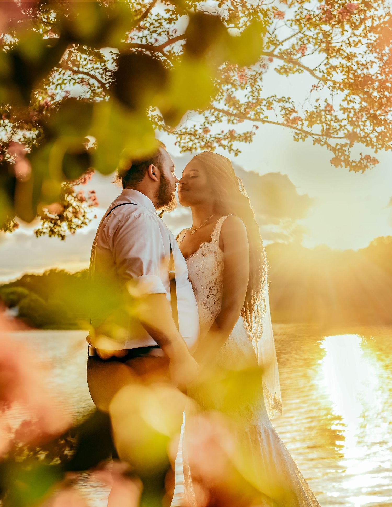Wedding couple kissing through blurred flowers and leaves, bright and artistic, photographed by Catch Your Fire Photography.