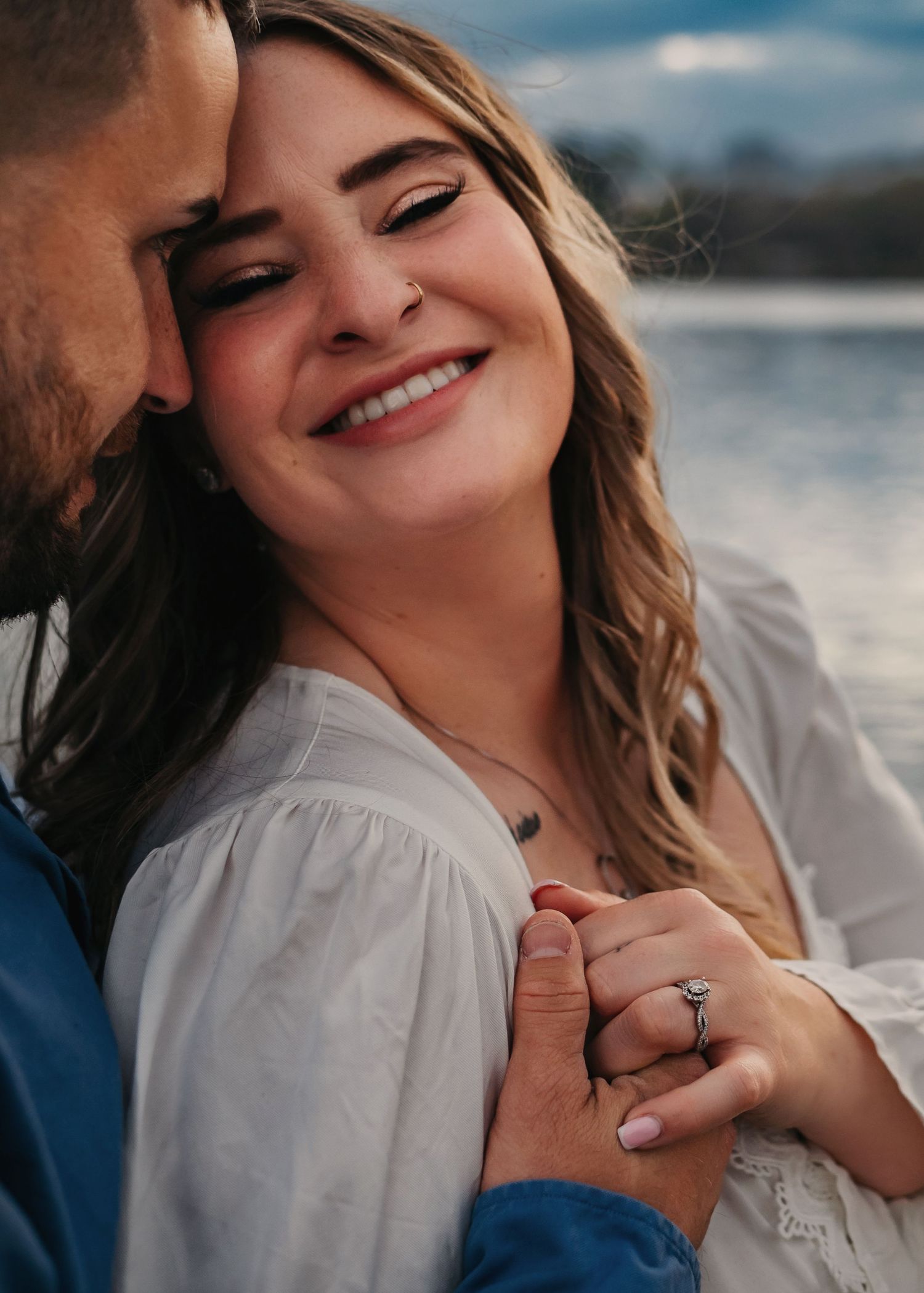 Lady Ann Lake engagement close-up, groom nuzzling bride’s cheek as she smiles and shows ring, captured by Catch Your Fire Photography.