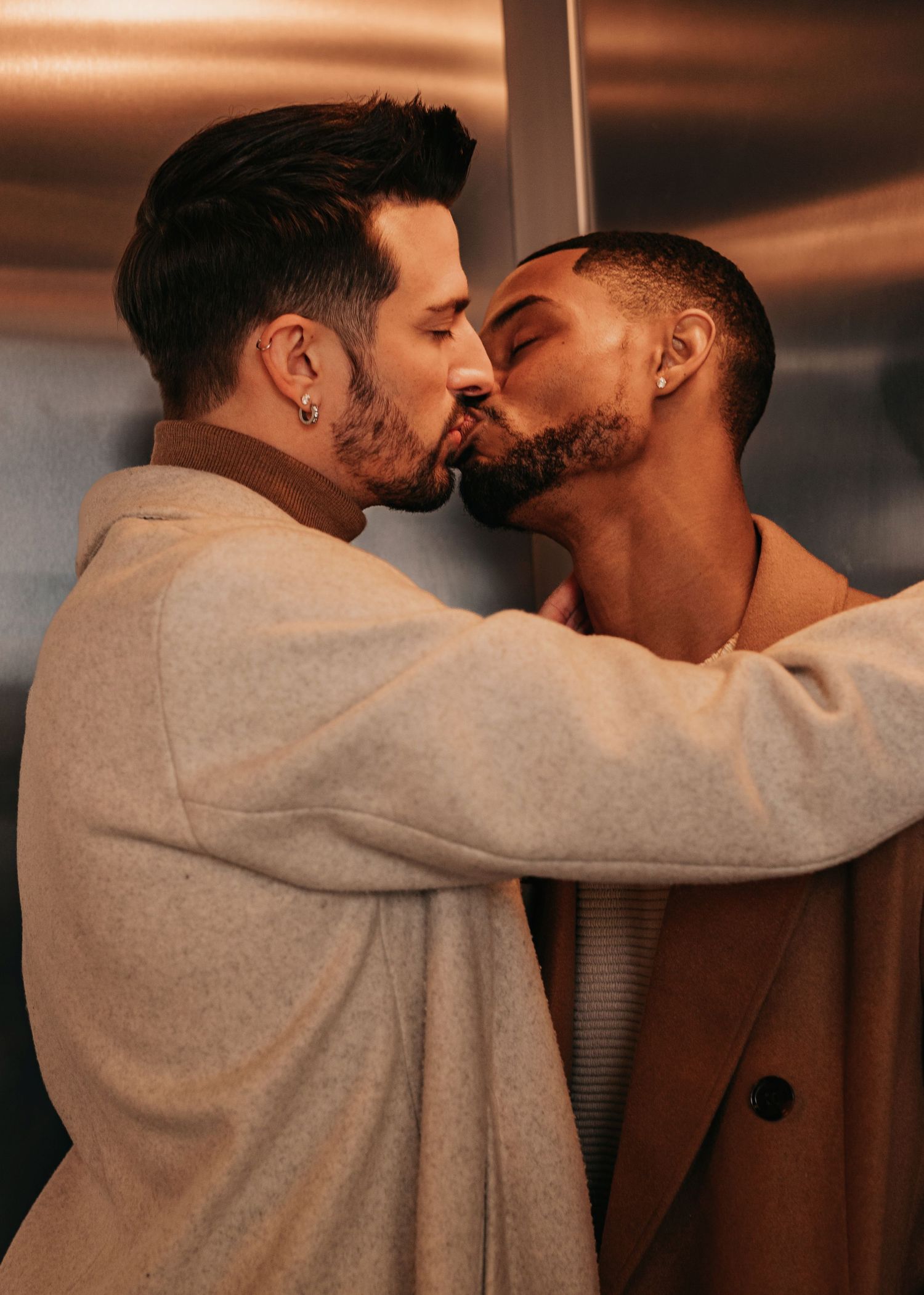 Two grooms sharing a kiss inside elevator at Bridge Street parking garage