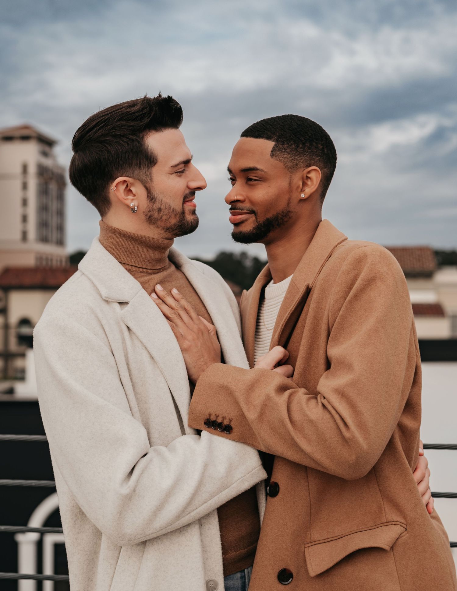 Same-sex couple looking at each other on parking garage rooftop overlooking Bridge Street in Huntsville