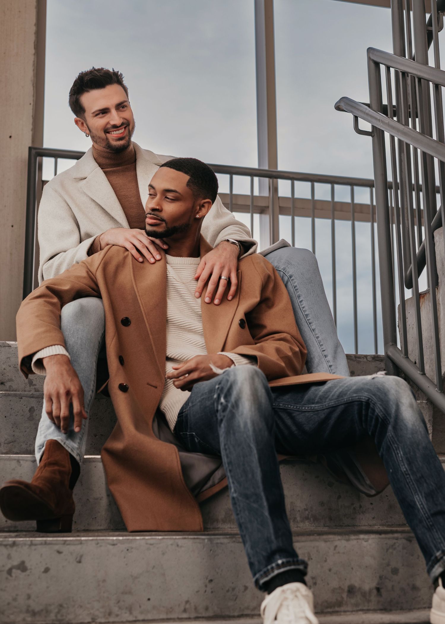 LGBTQ+ couple sitting on parking garage stairs cuddling during Bridge Street engagement session