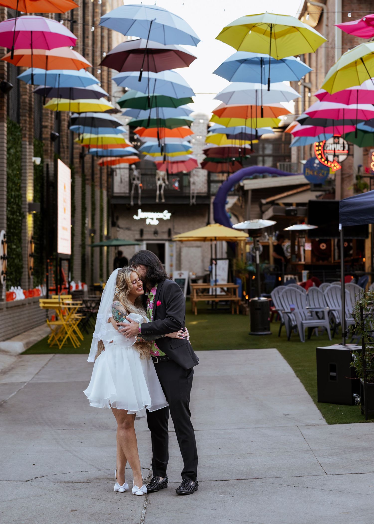 Eloping couple sharing a moment at Jefferson Alley with colorful hanging umbrellas in downtown Huntsville, captured by Catch Your Fire Photo