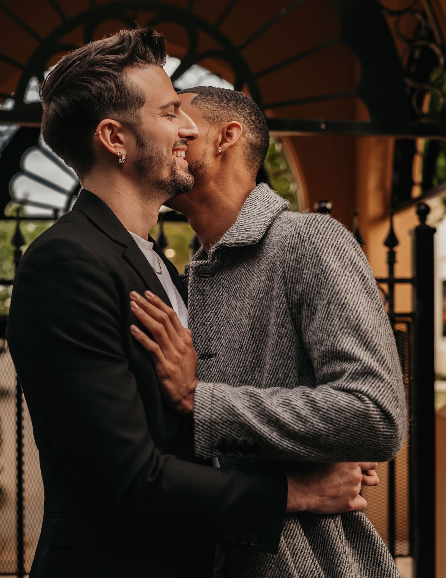 candid moment of LGBTQ+ couple cuddling together with soft sunset glow in courtyard
