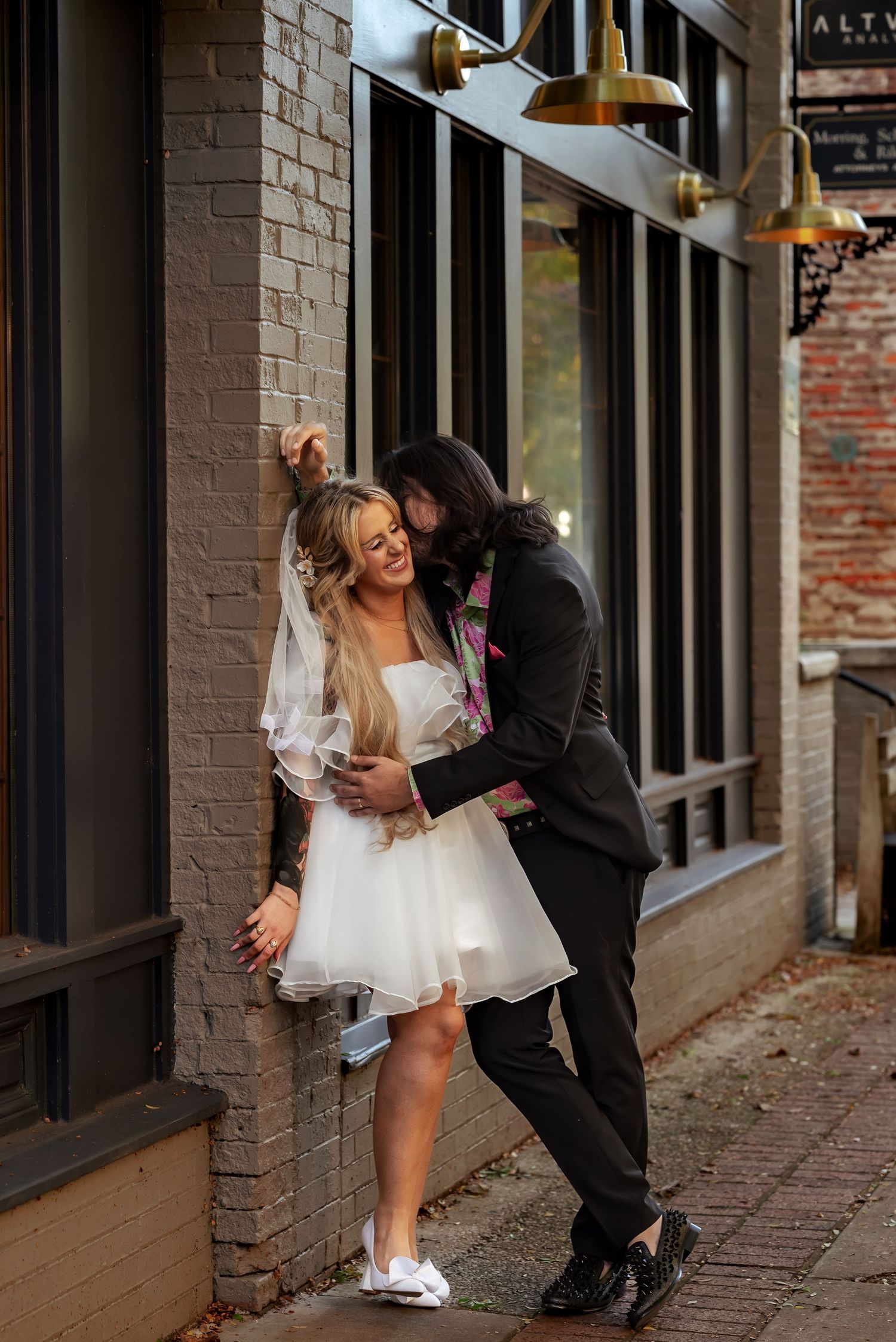 Candid downtown elopement portrait with groom kissing bride’s neck while she laughs
