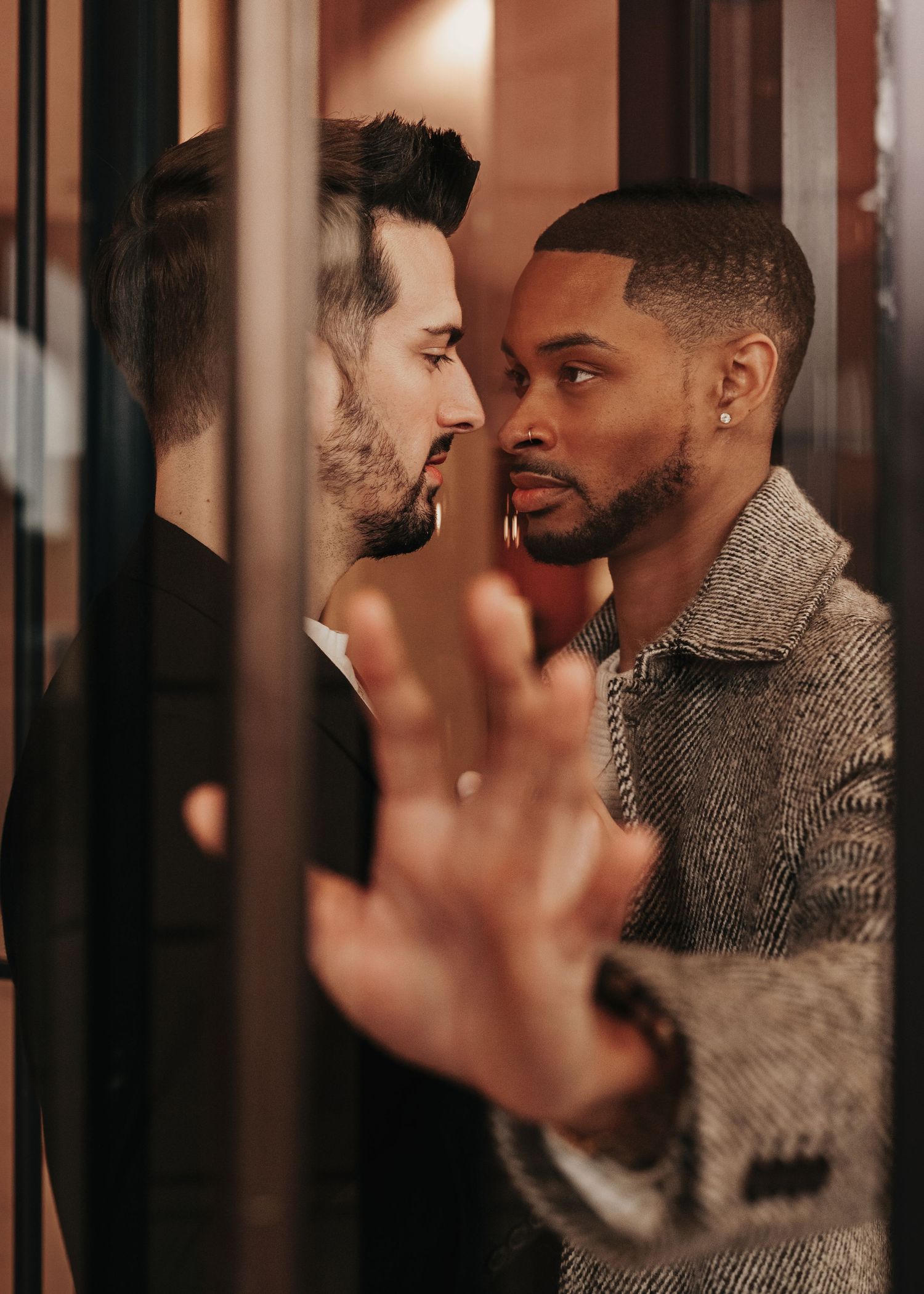 Candid, intimate moment between two grooms in rotating doors at The Westin Huntsville hotel at Bridgestreet