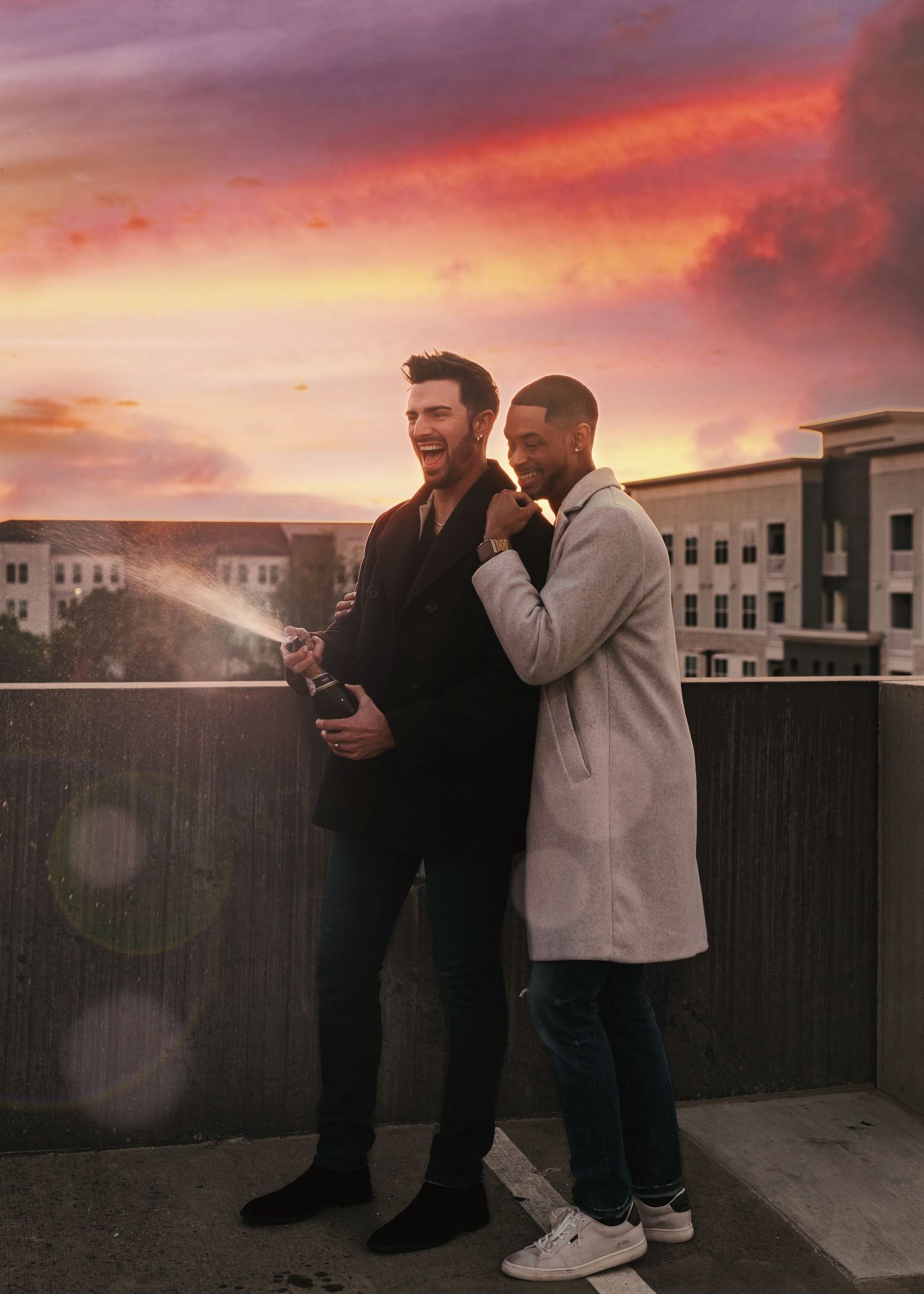 Playful champagne spray moment during rooftop LGBTQ+ engagement session in Huntsville Alabama