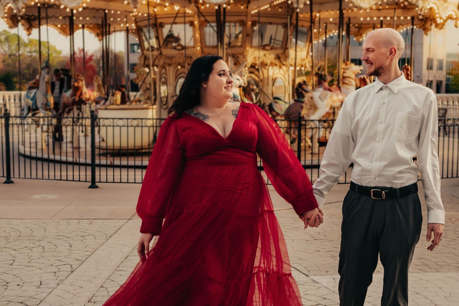 Couple walking hand in hand in front of carousel at Bridge Street captured by Catch Your Fire Photography in Huntsville, AL.