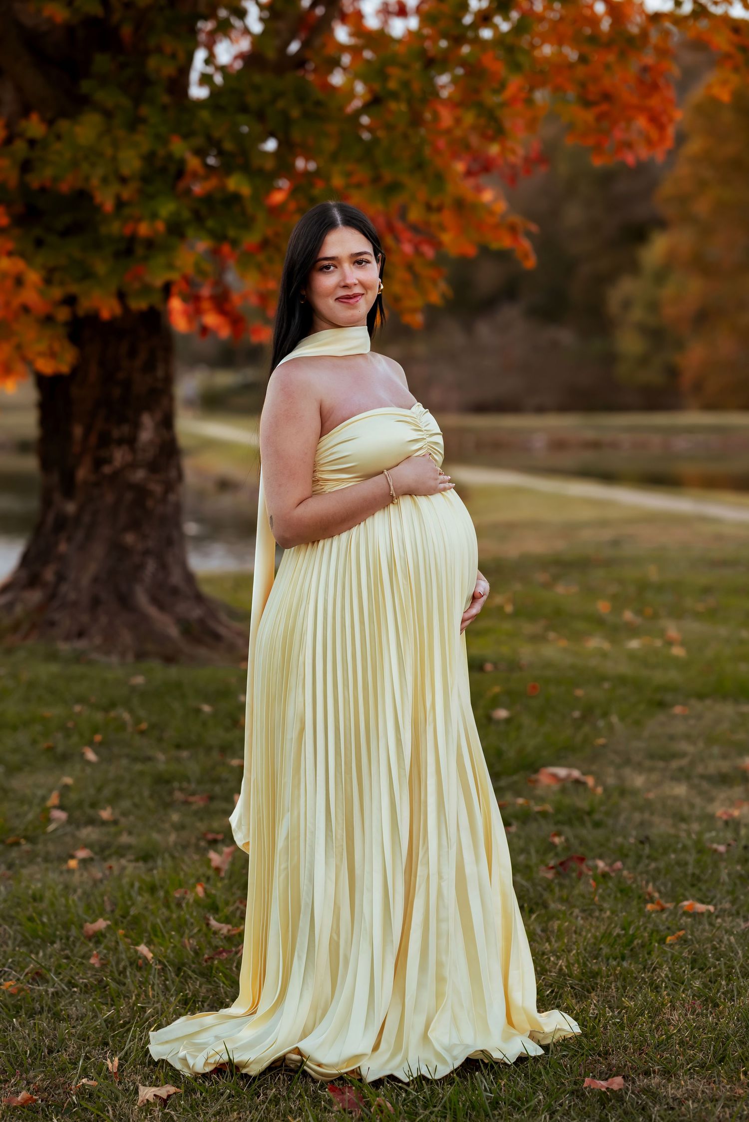 elegant editorial maternity session with her wearing a soft yellow gown holding belly with colorful fall background at Lady Ann Lake