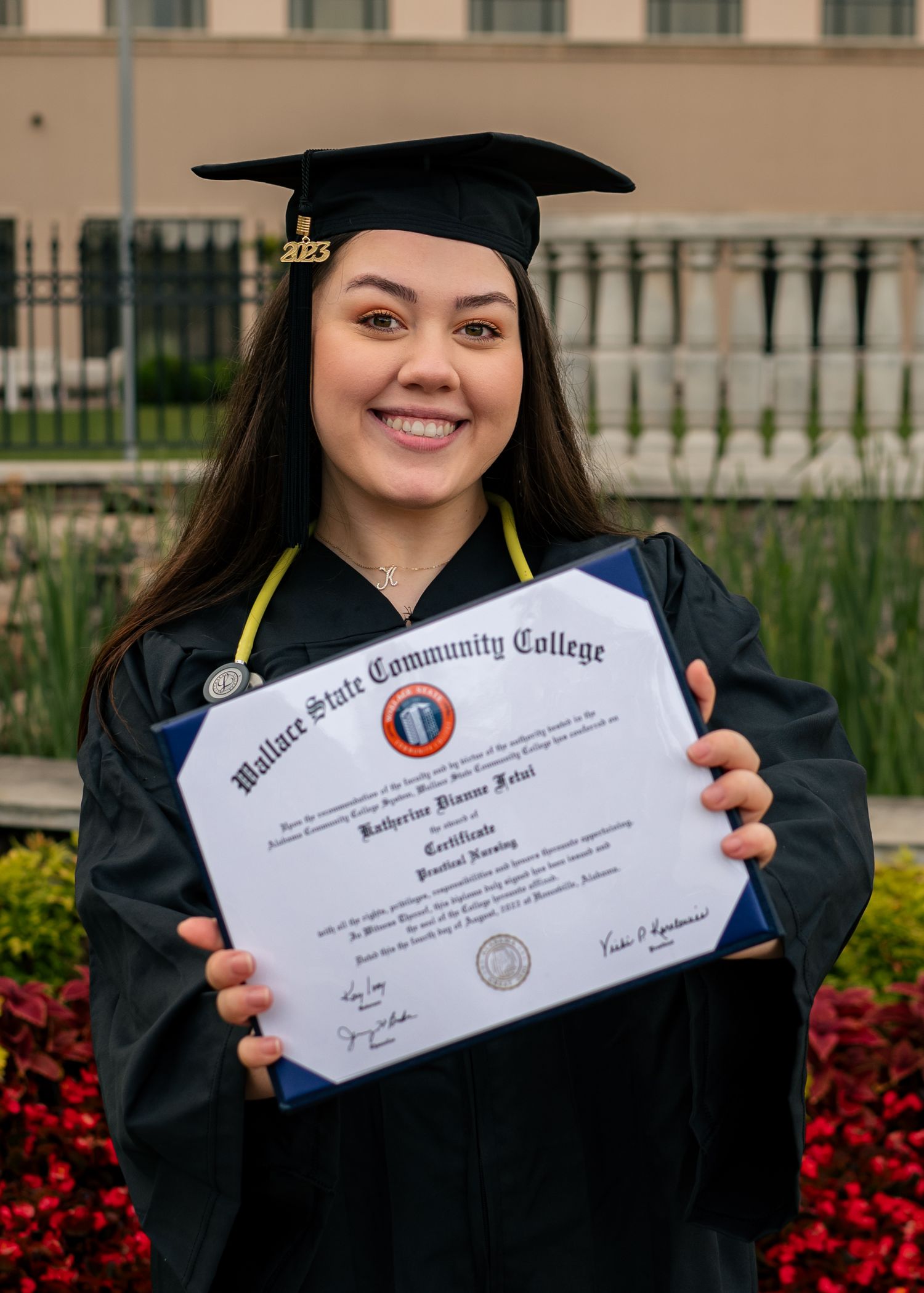 Smiling college grad shows off her diploma at Bridge Street Town Centre in Huntsville, captured by Catch Your Fire Photography.