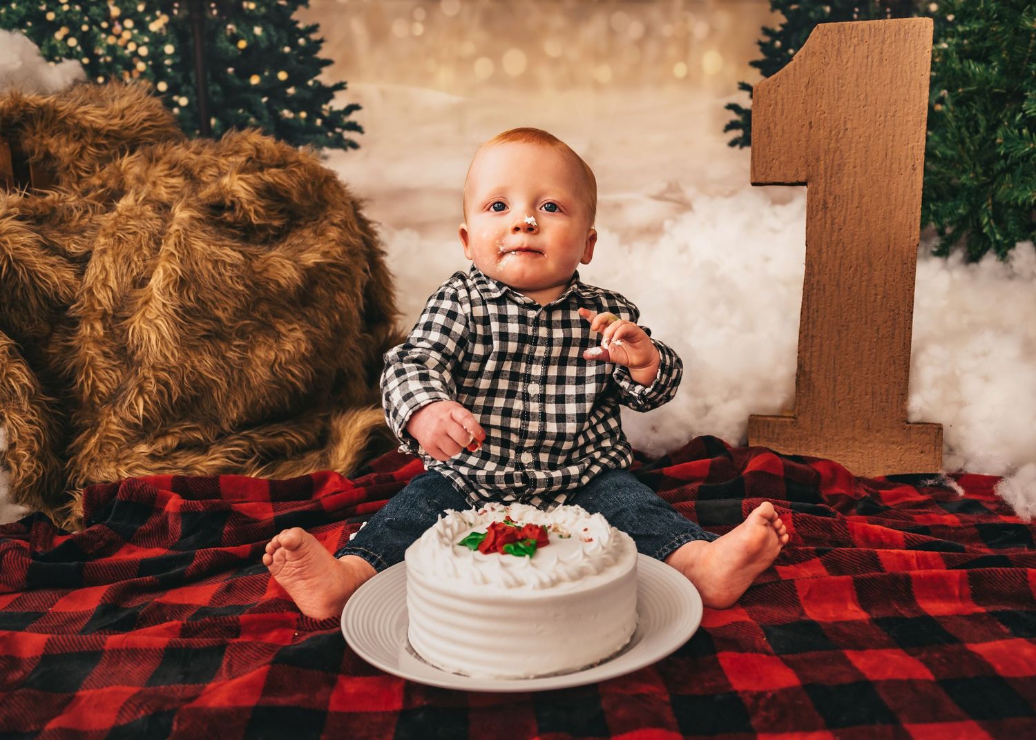 studio cake smash themed for winter for a cute little lumberjack with fur, red plaid, and a wooden number one and fake snow fluff in Madison
