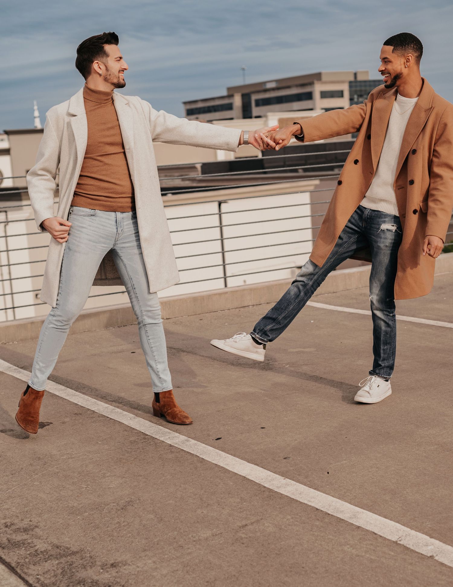 Same-sex couple holding hands, twirling, and laughing together on parking garage rooftop