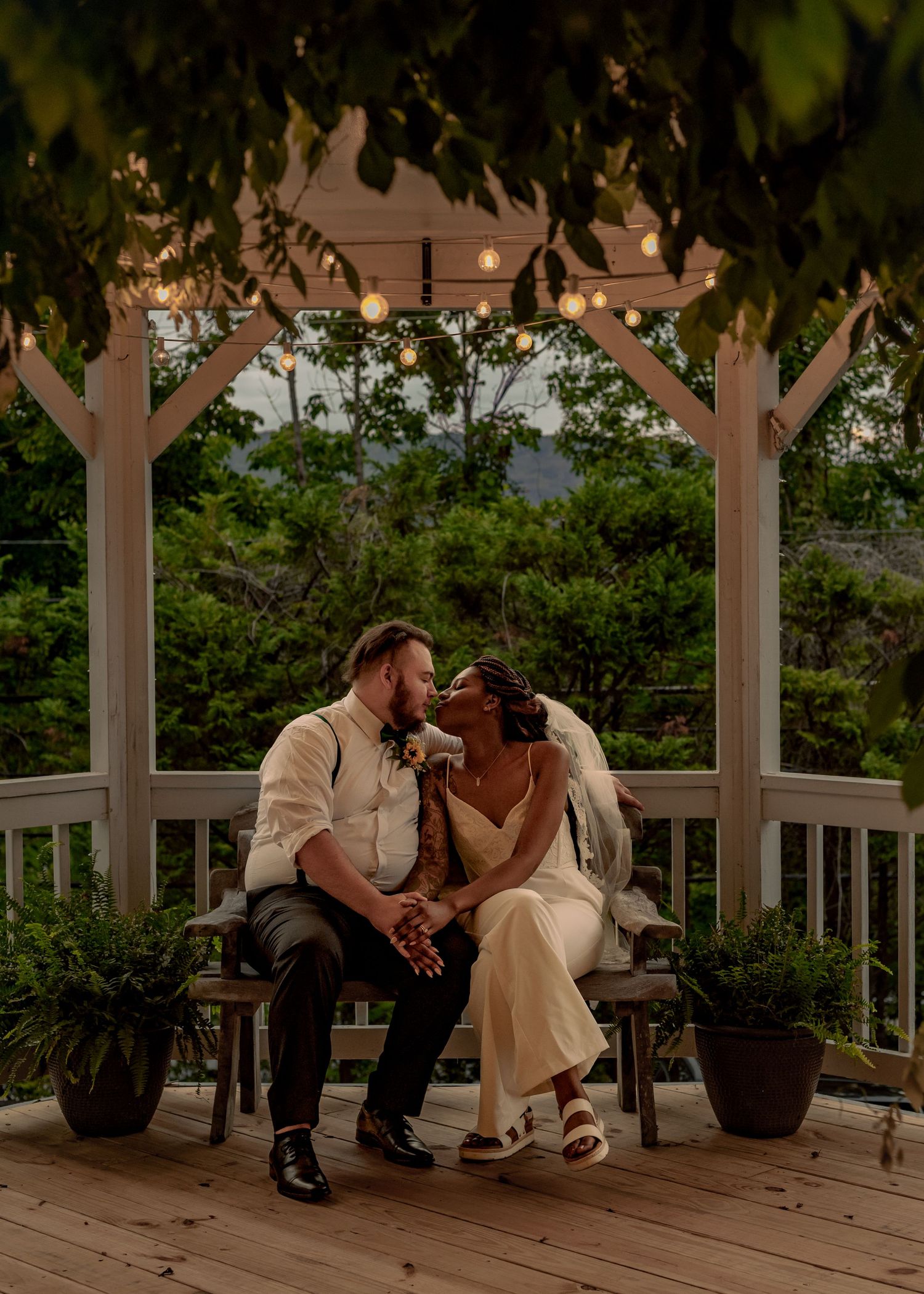 Bride and groom sitting in gazebo at dusk with glowing fairy lights and lush greenery at Wedding Chapel on the Mountain, Huntsville, AL