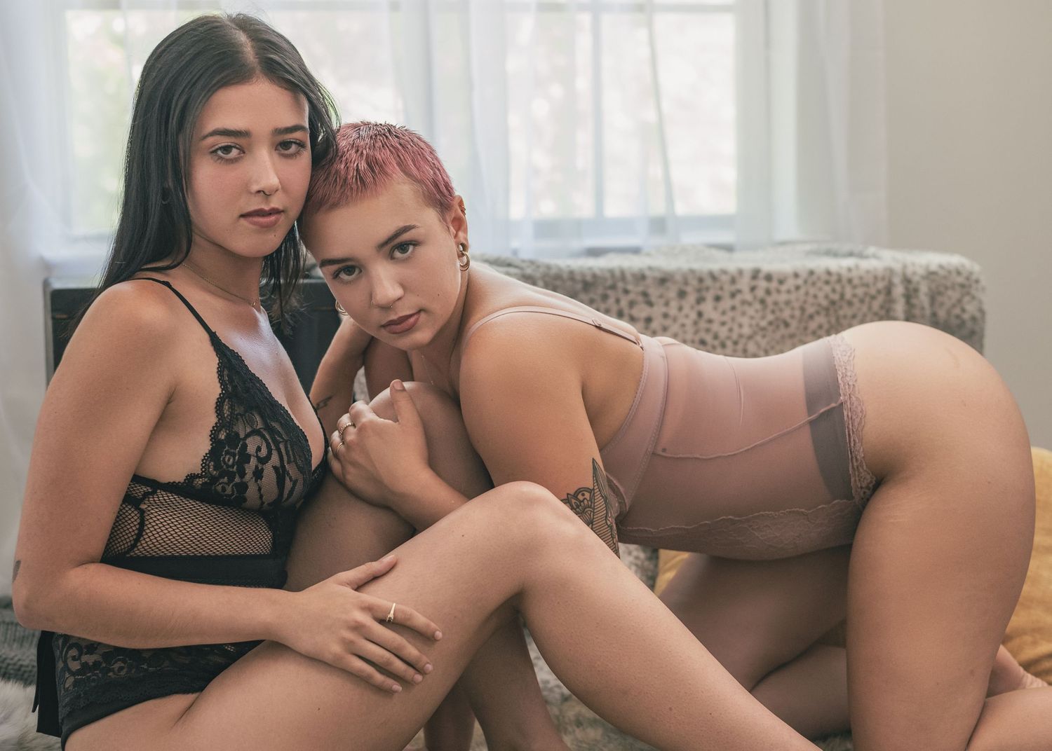LGBTQ studio boudoir session with two girls in lingerie, one girl sitting, the other crawling to her and grabbing her leg in Huntsville, AL.