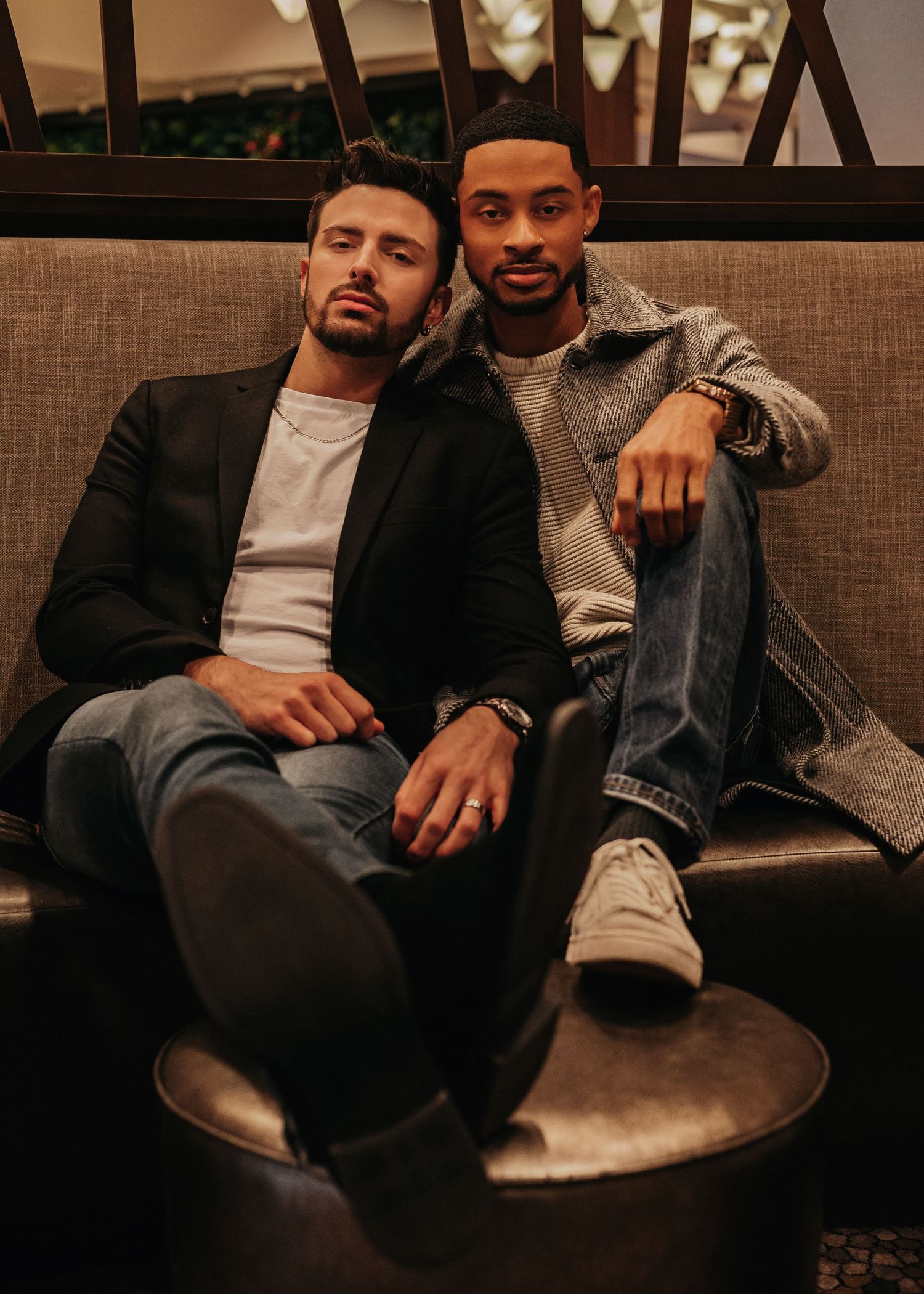 Two grooms cuddling together on couch inside The Westin Huntsville lobby