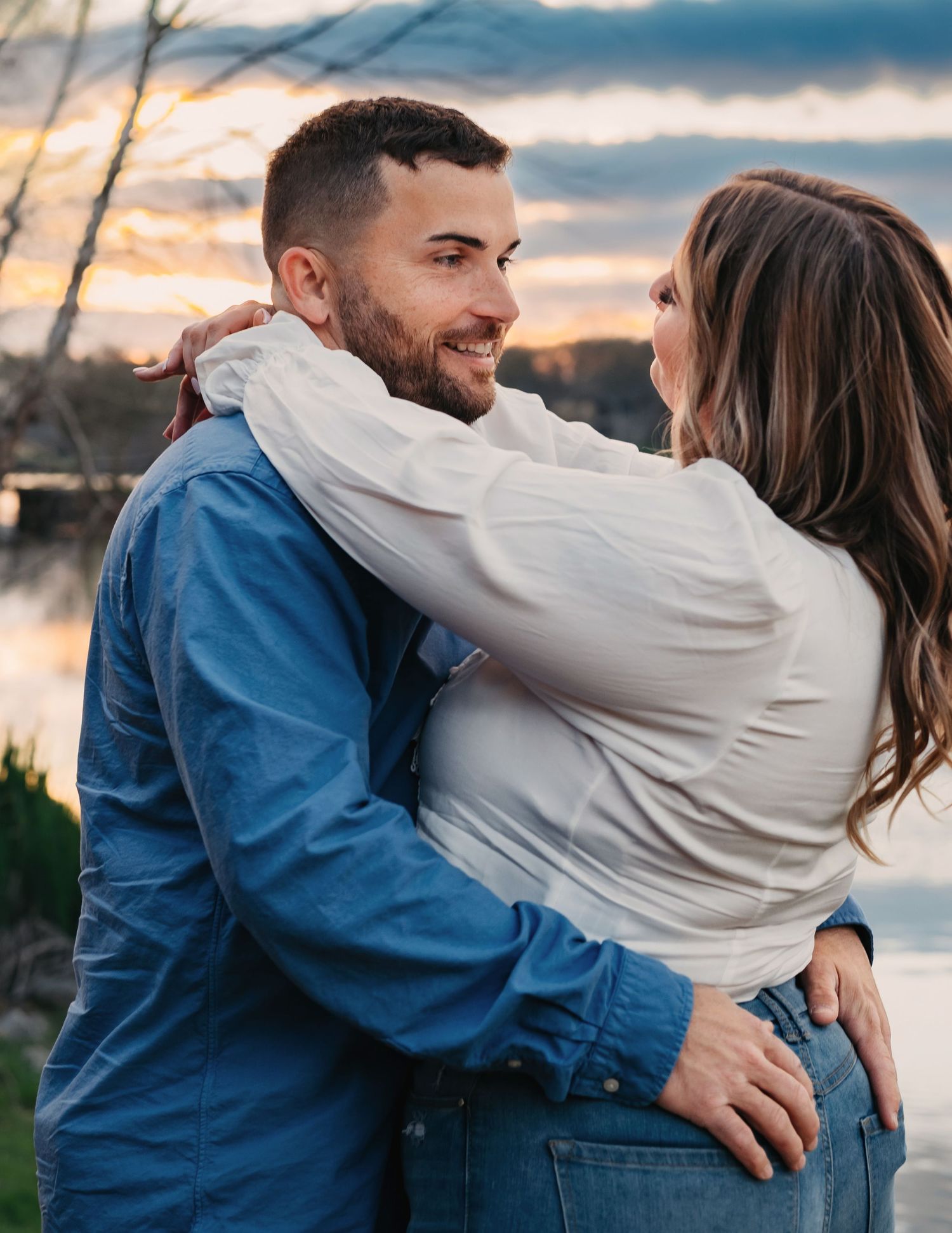 Moody, Lady Ann Lake engagement close-up of couple hugging and gazing at each other under blue and yellow cloudy sunset sky in Huntsville.
