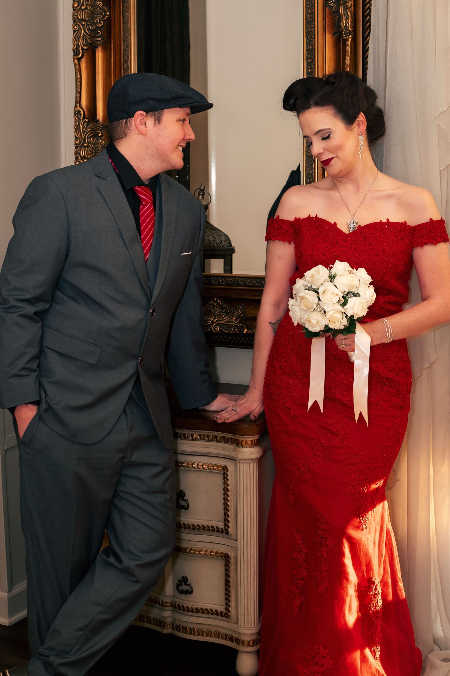 Tender moment at New Year’s Eve wedding, bride in red dress blushing as groom whispers to her, captured by Catch Your Fire Photography.