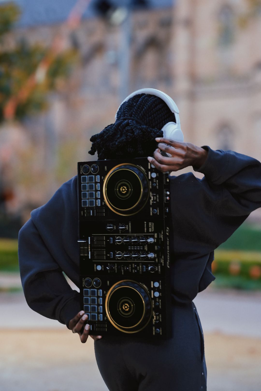 Woman carrying Pioneer DJ controller on her back outdoors.