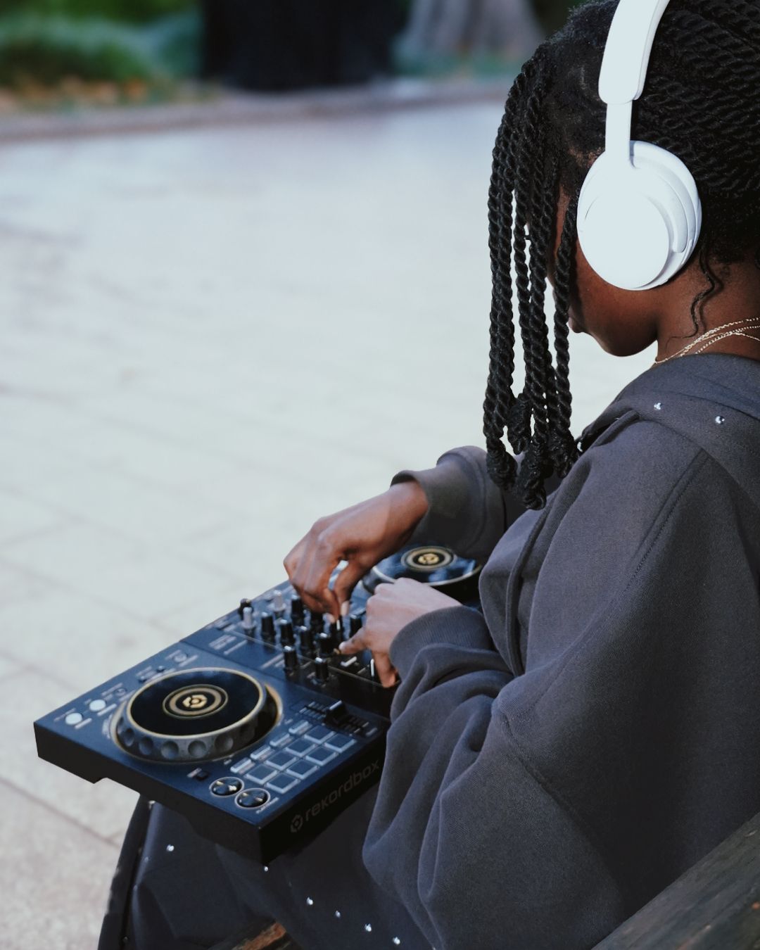 Female DJ using Pioneer controller while wearing white headphones.